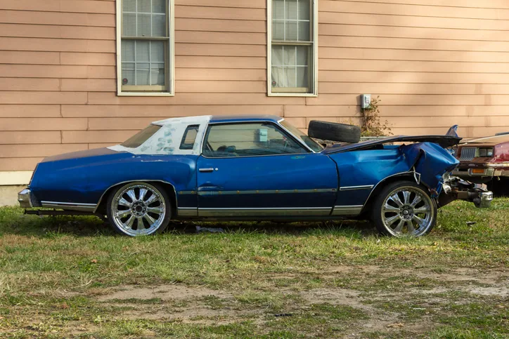Old damaged car parked beside a house, ready for junk car removal